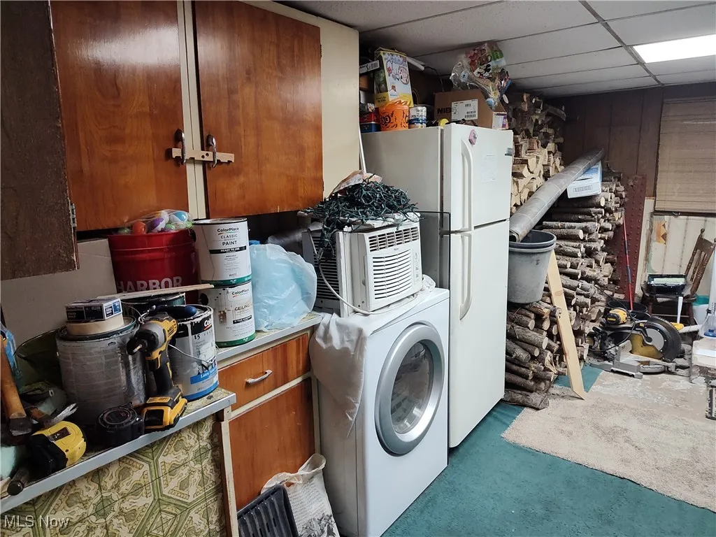 Washroom featuring a paneled ceiling, washer / dryer, and wooden walls