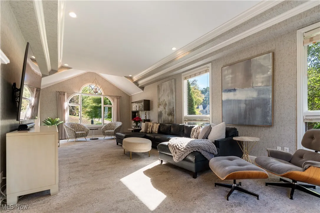 Spectacular family room featuring wallpapered walls, a lofted ceiling,  plenty of natural light, and crown molding.