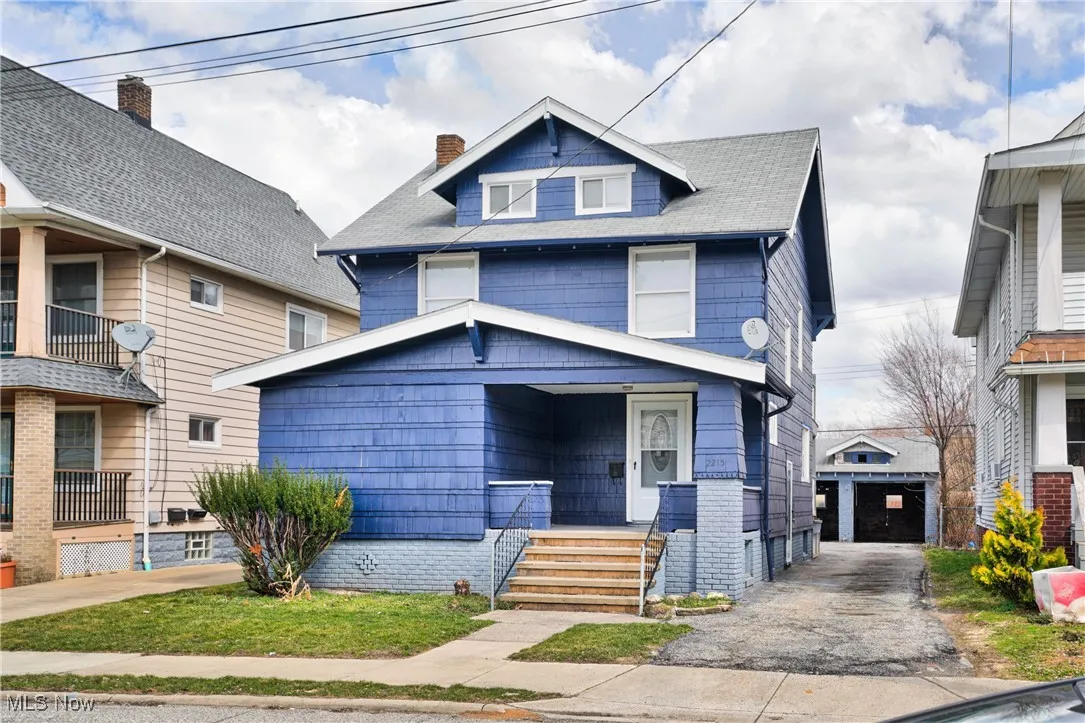American foursquare style home featuring a chimney, an outdoor structure, and a garage