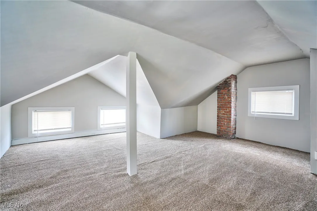 Bonus room featuring lofted ceiling, carpet flooring, and a baseboard heating unit