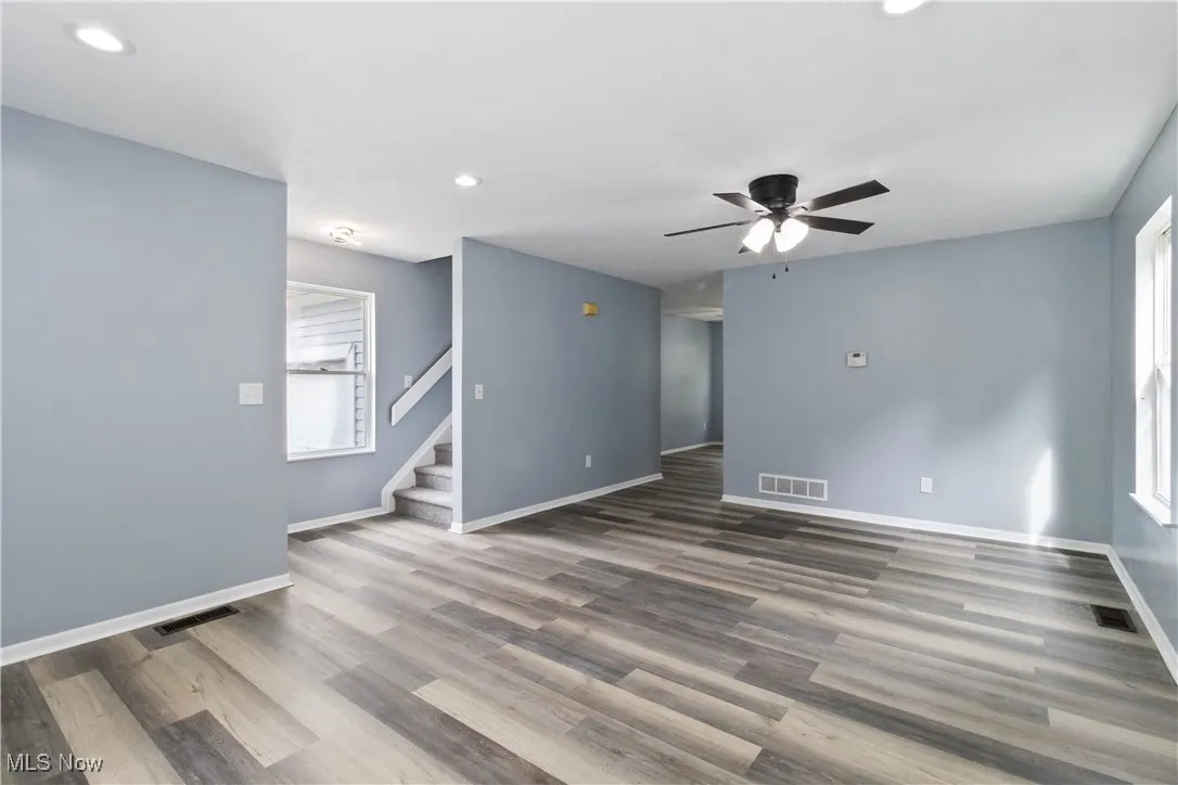 Unfurnished living room featuring recessed lighting, wood finished floors, stairs, and ceiling fan