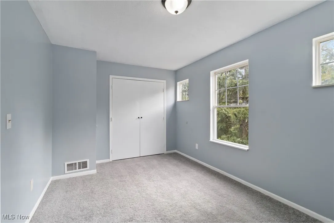 Unfurnished bedroom with light carpet and a closet