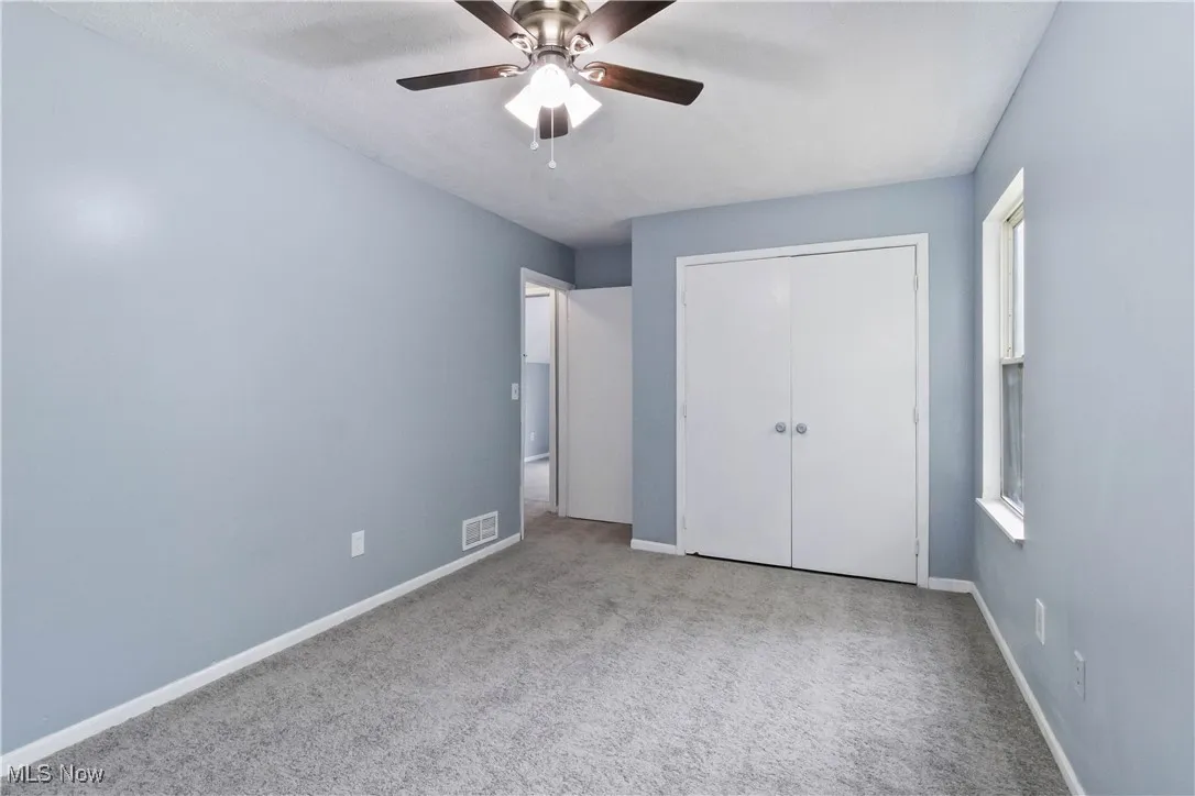 Unfurnished bedroom featuring carpet flooring, ceiling fan, and a closet