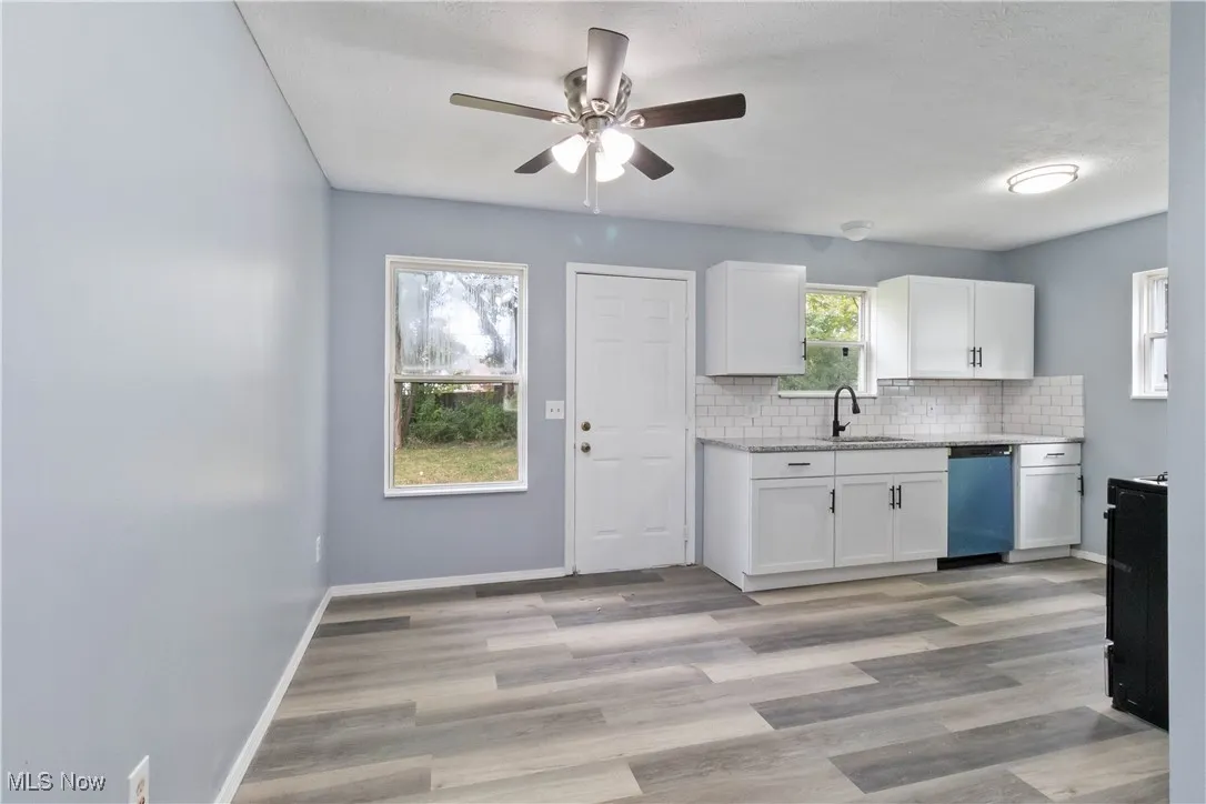Kitchen featuring white cabinets, tasteful backsplash, dishwasher, light wood-style flooring, and ceiling fan