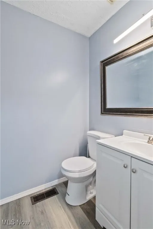 Bathroom with a textured ceiling, vanity, and light wood-style flooring