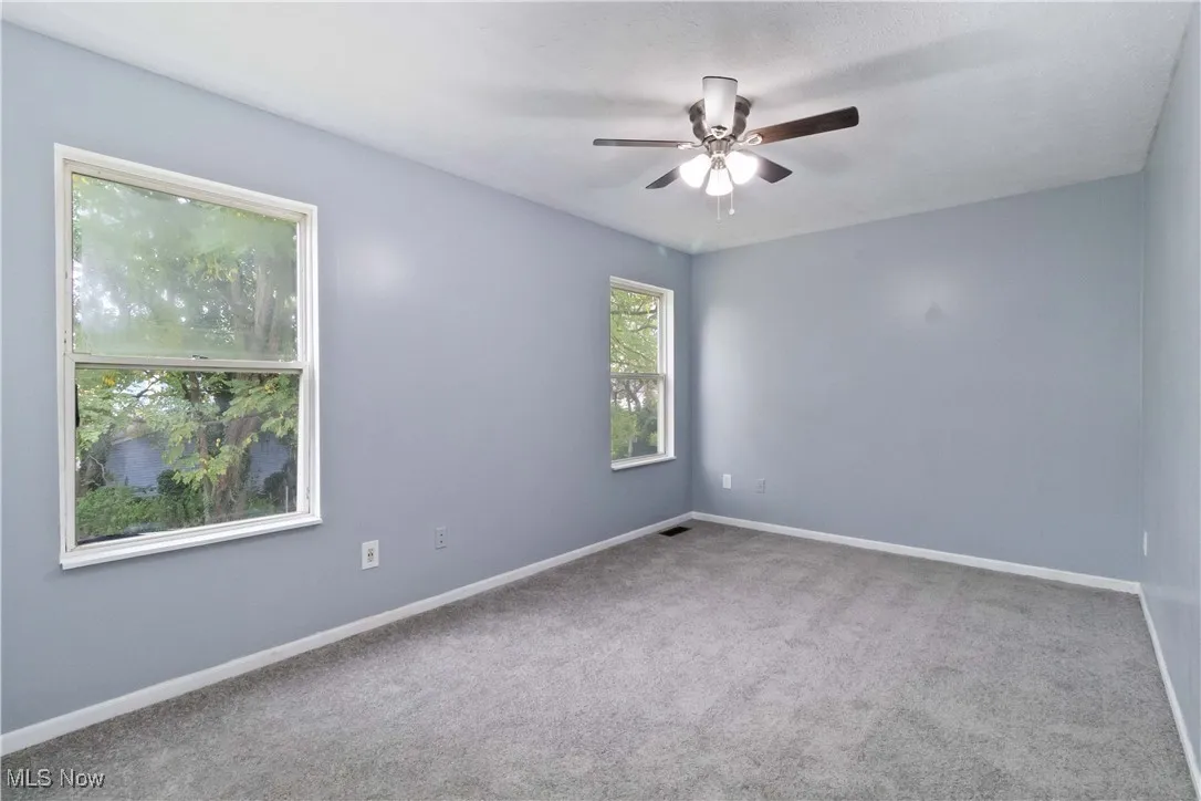 Carpeted spare room featuring baseboards and ceiling fan
