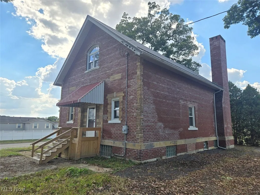 View of side of home with brick siding and a chimney