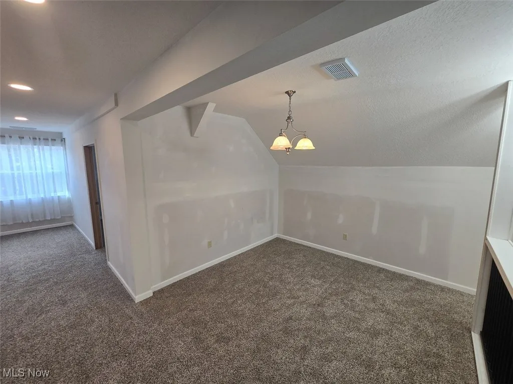 Bonus room with carpet floors, a textured ceiling, and lofted ceiling
