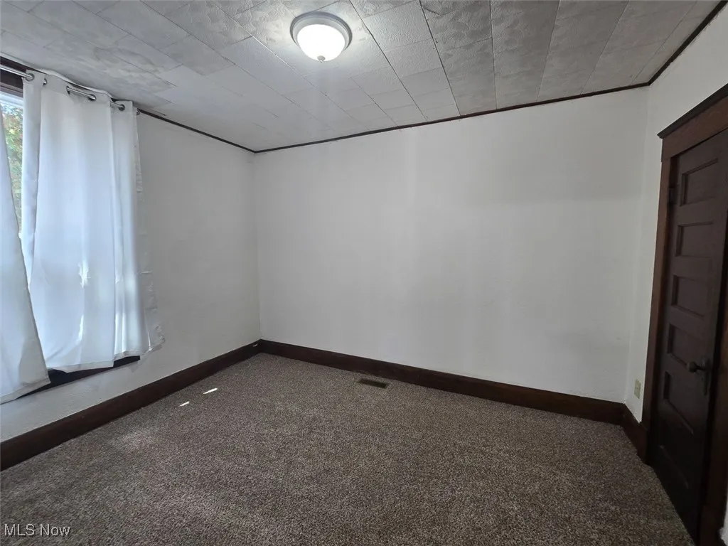 Spare room featuring baseboards and dark colored carpet