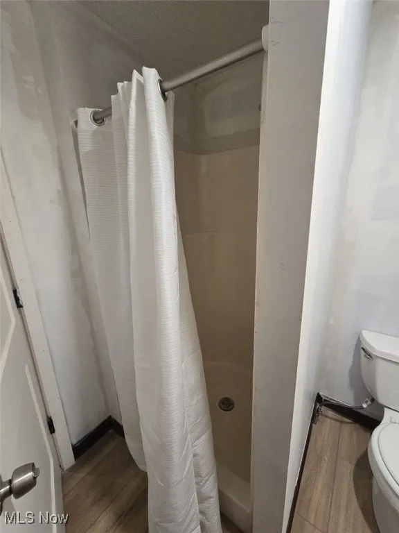 Bathroom with dark wood-style floors and a shower stall