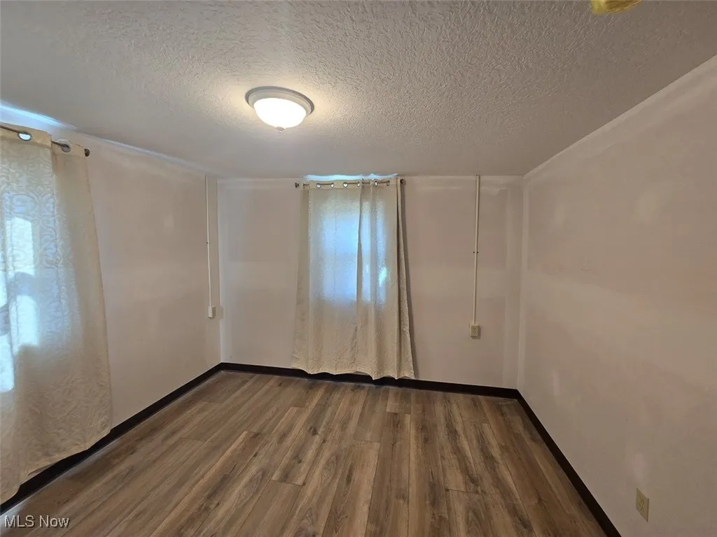 Empty room with dark wood finished floors and a textured ceiling