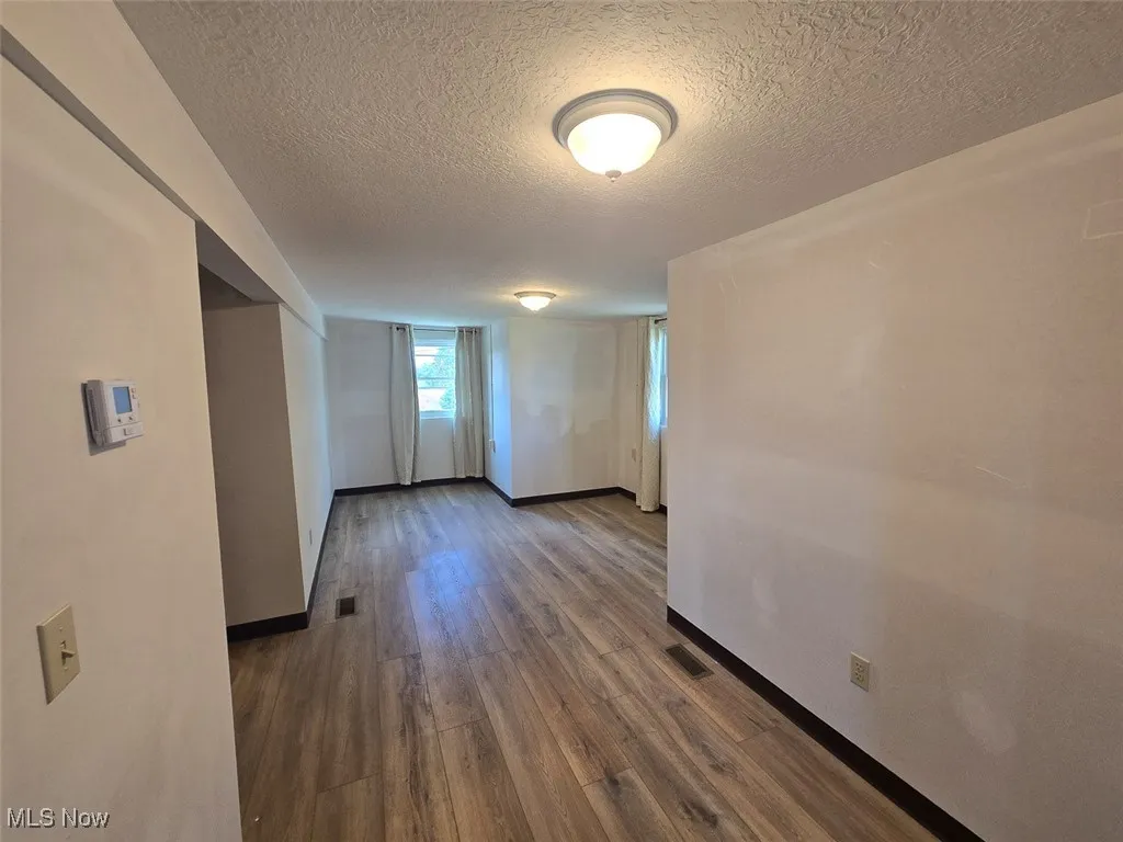 Unfurnished room featuring wood finished floors and a textured ceiling
