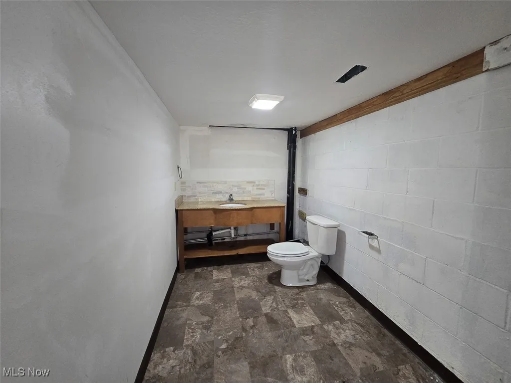 Bathroom featuring vanity, stone finish flooring, and concrete block wall