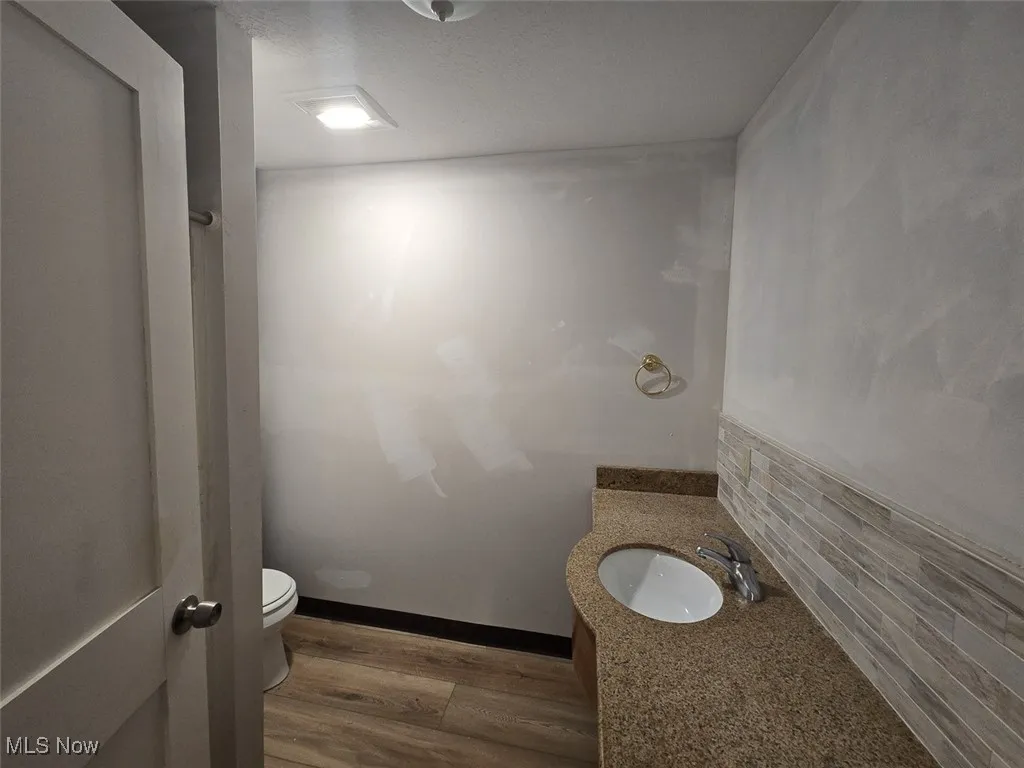 Half bathroom with dark wood-type flooring, vanity, and a textured ceiling