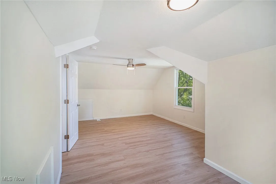 Additional living space featuring light wood-type flooring, lofted ceiling, and ceiling fan