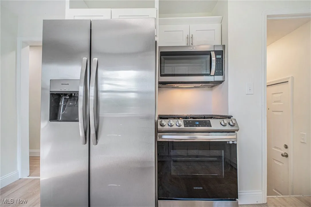 Kitchen featuring stainless steel appliances, light wood-style floors, and white cabinets