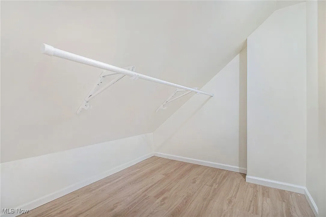 Spacious closet featuring light wood-type flooring and vaulted ceiling