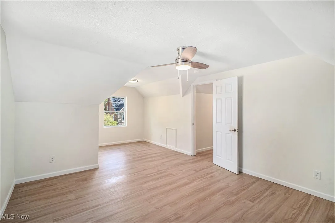 Additional living space featuring vaulted ceiling, light wood-type flooring, ceiling fan, and a textured ceiling