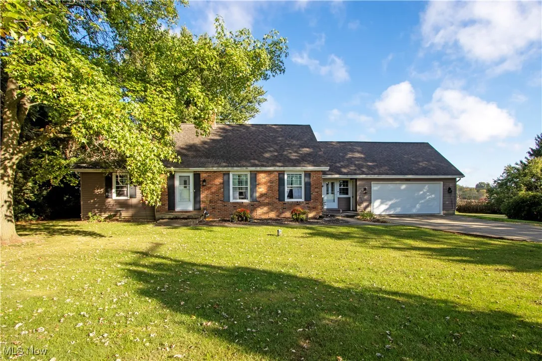 Ranch-style house featuring driveway, a front lawn, brick siding, and an attached garage