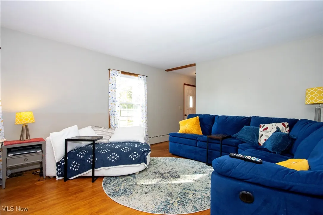 Living room with wood finished floors and a baseboard heating unit