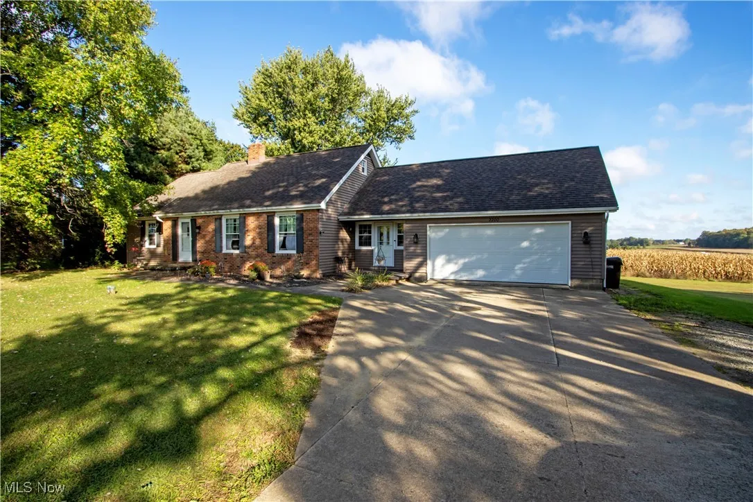 View of front of house with a front lawn, concrete driveway, a chimney, and an attached garage