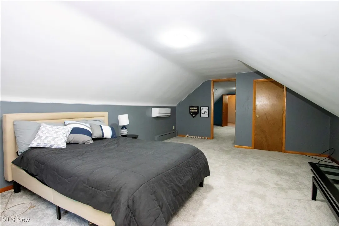 Bedroom featuring lofted ceiling, light carpet, and a baseboard radiator
