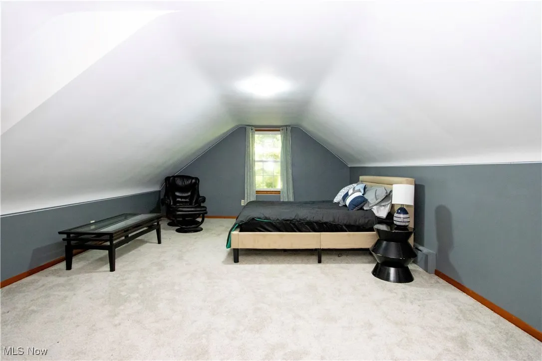 Carpeted bedroom with baseboards and vaulted ceiling