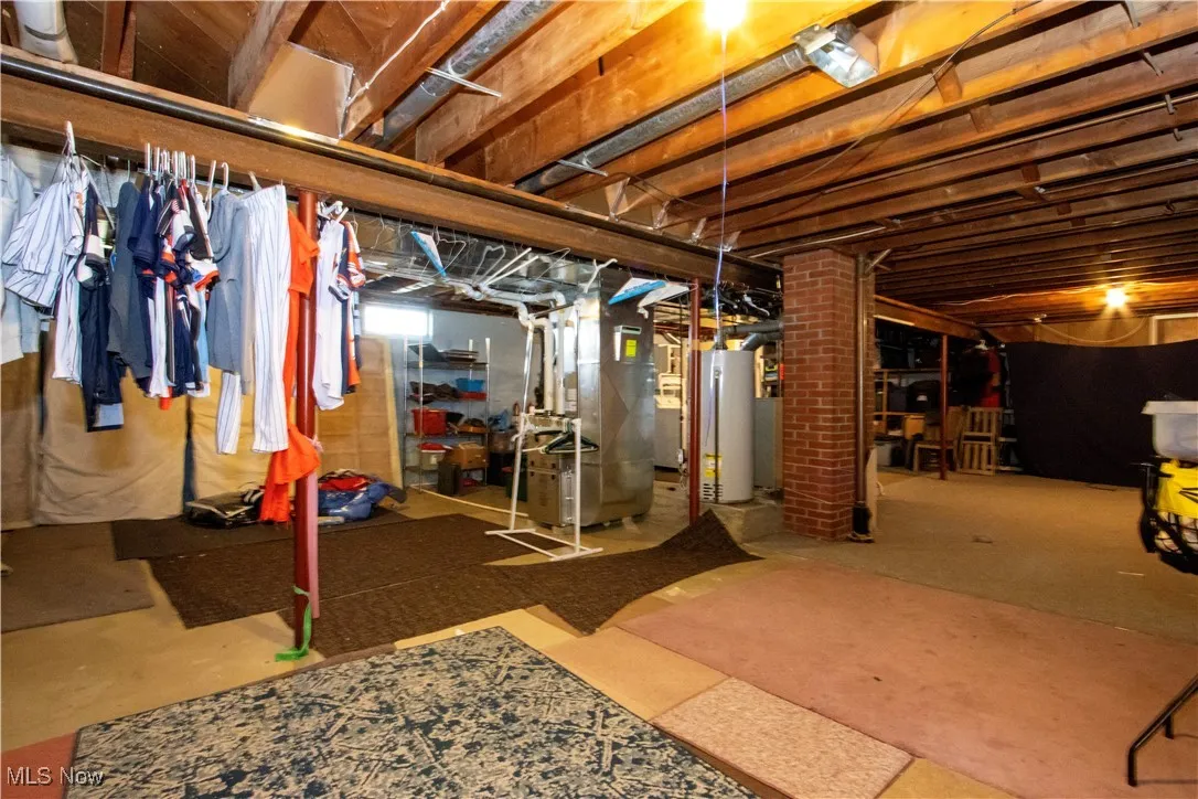 Unfinished below grade area featuring heating unit and water heater
