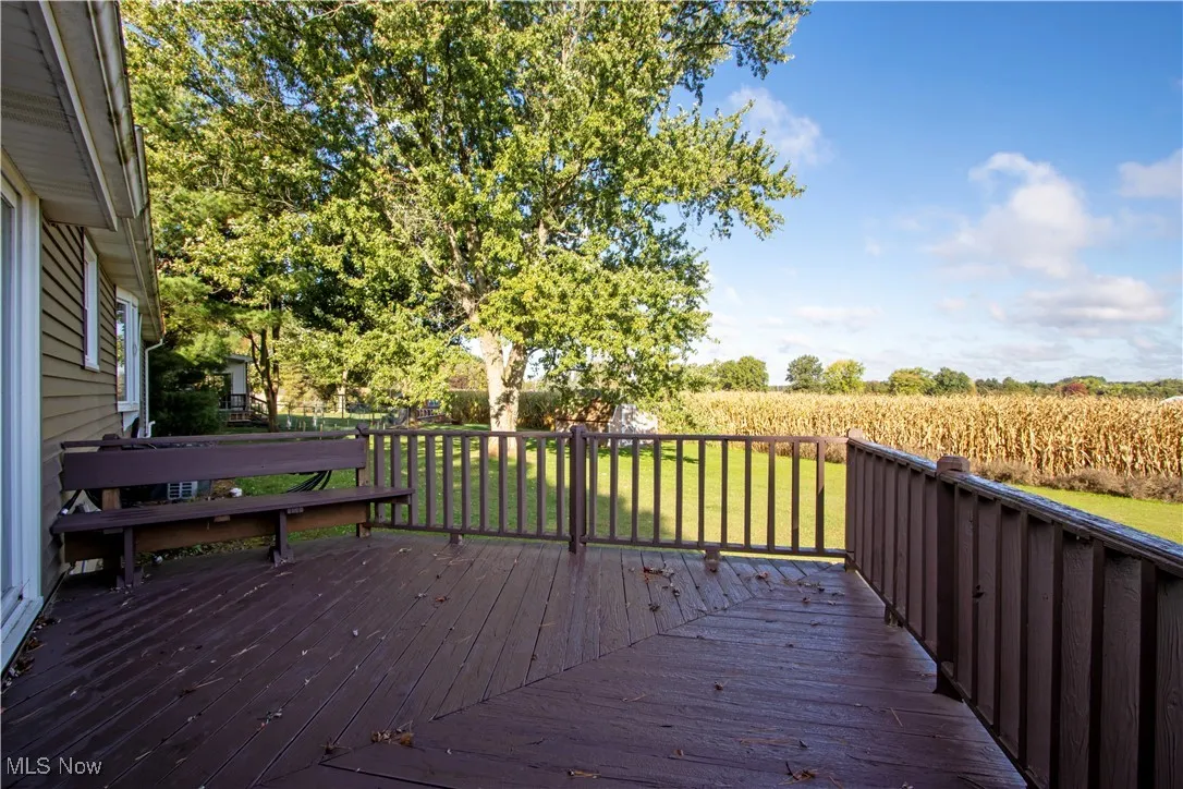 Wooden deck with a lawn, agricultural area, and a view of countryside