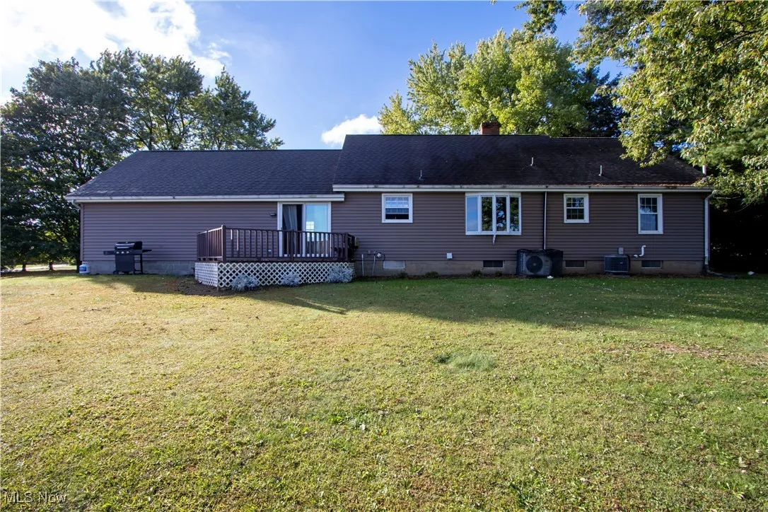 Back of house with a deck, a yard, and a chimney