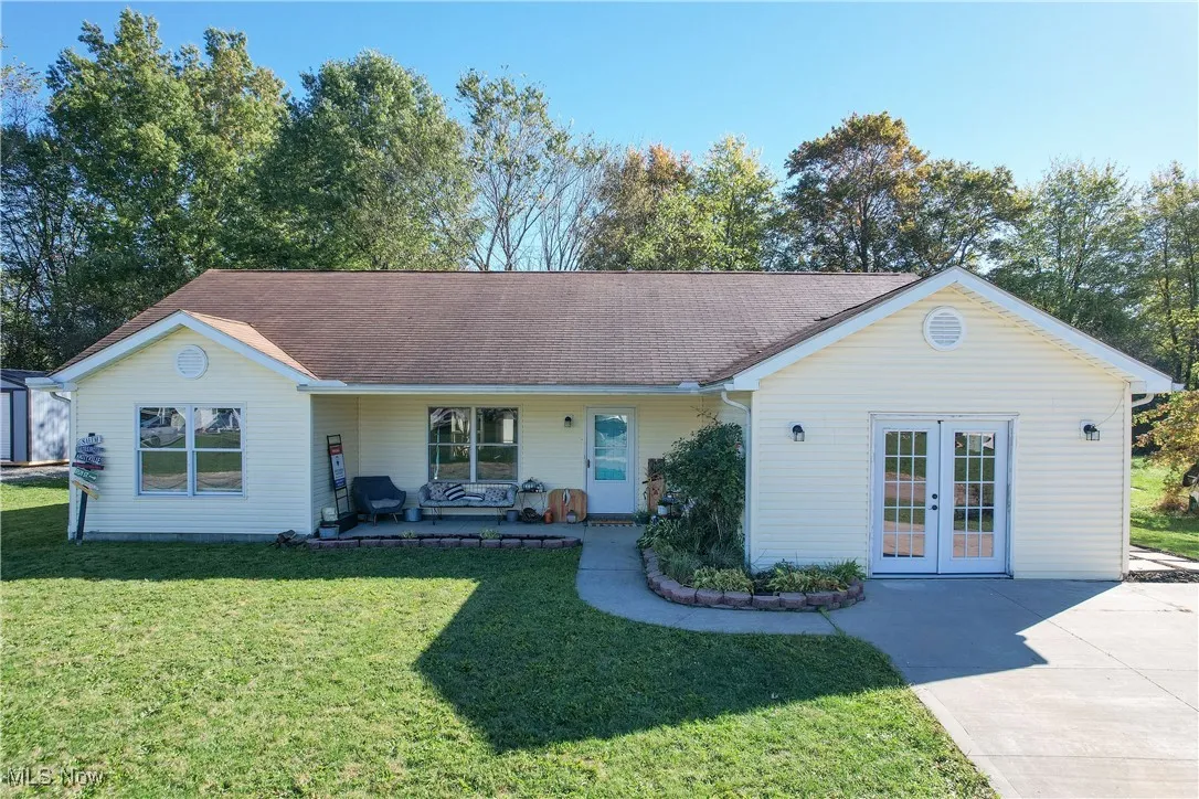 Ranch-style house with a porch, a front yard, french doors, and roof with shingles