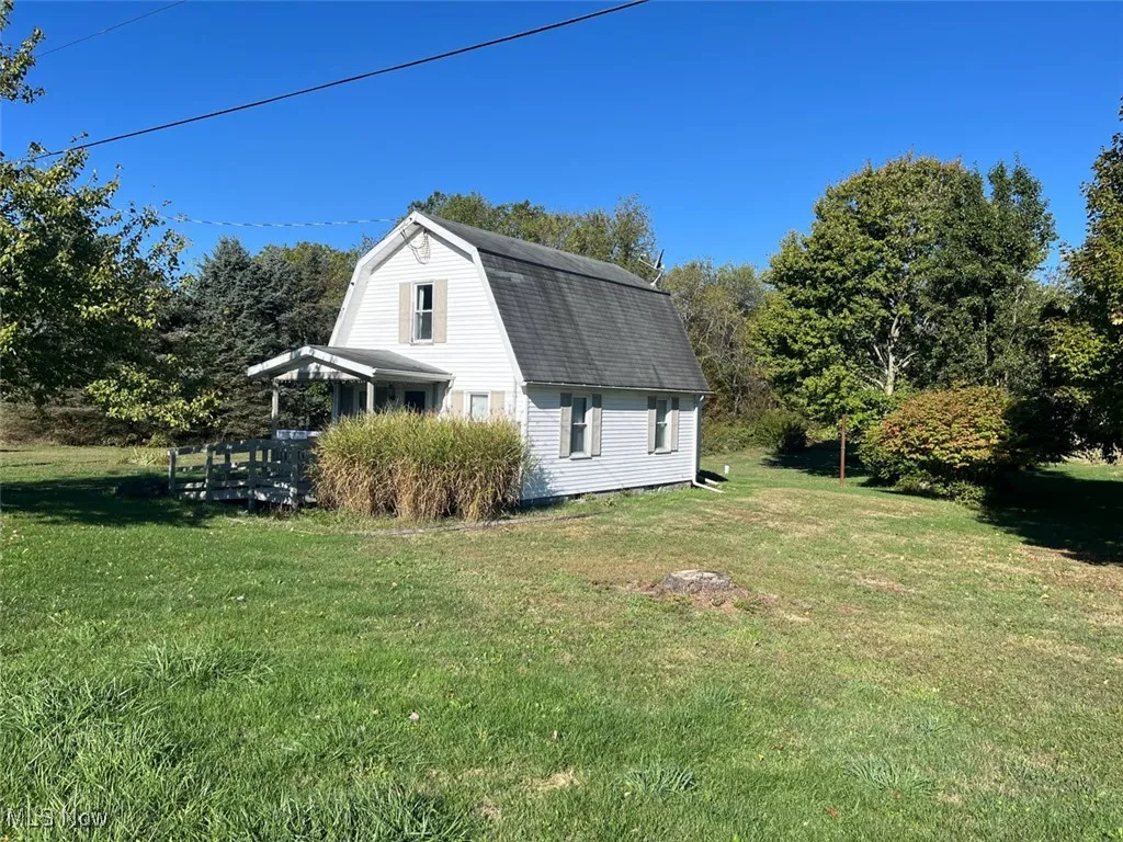 View of home's exterior featuring a gambrel roof and a yard