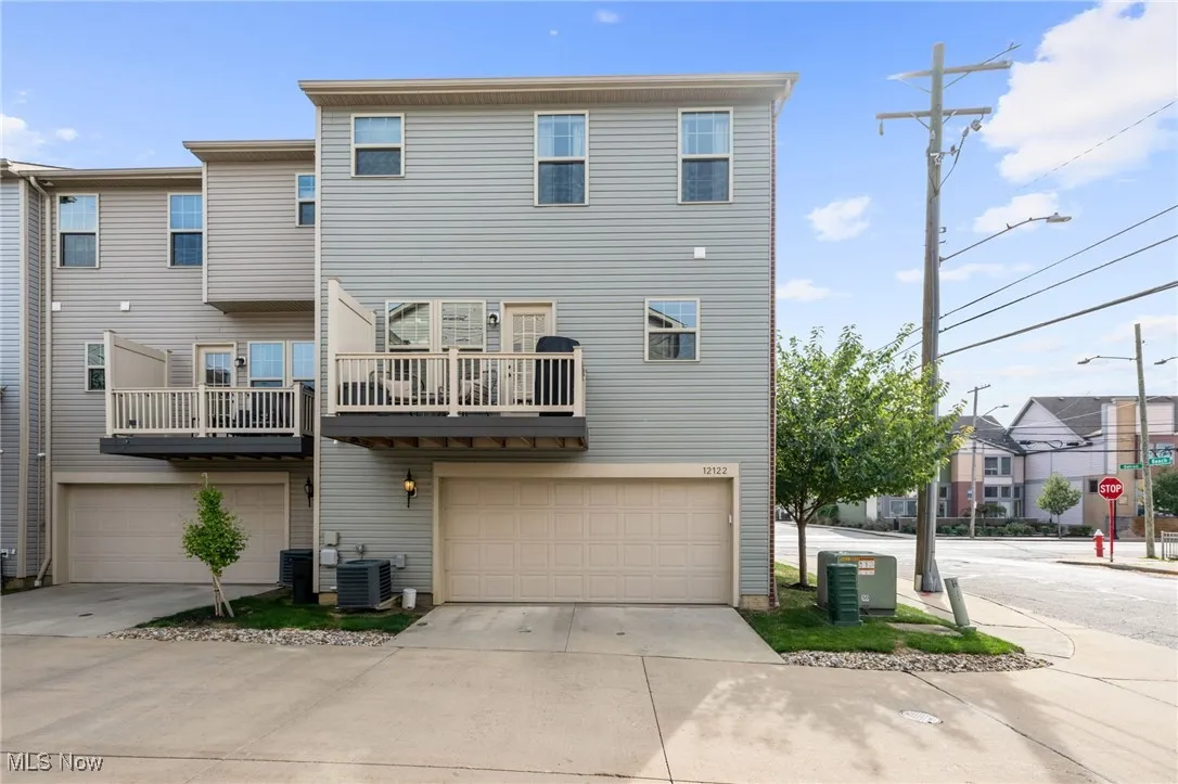 Back of property featuring concrete driveway, a balcony, and an attached garage