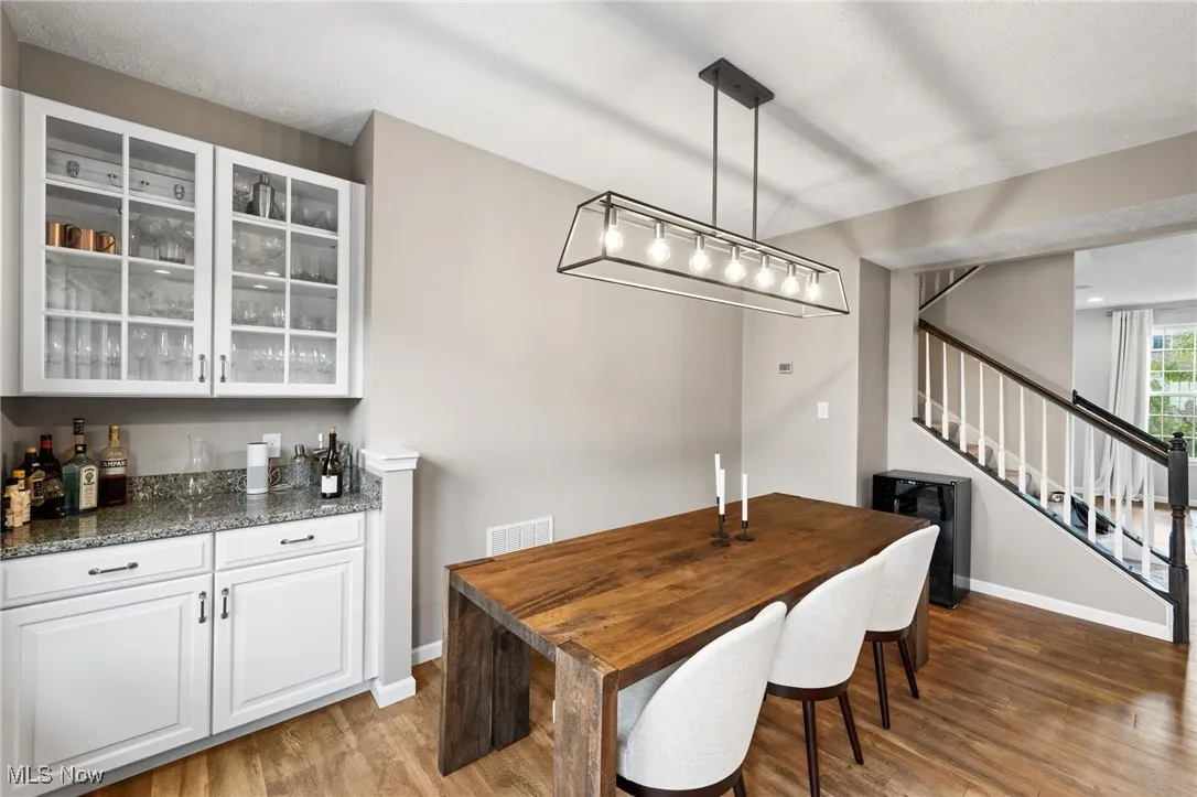 Dining area with light wood-type flooring, stairway, and a bar