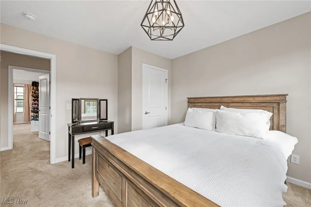 Bedroom with light colored carpet and a chandelier