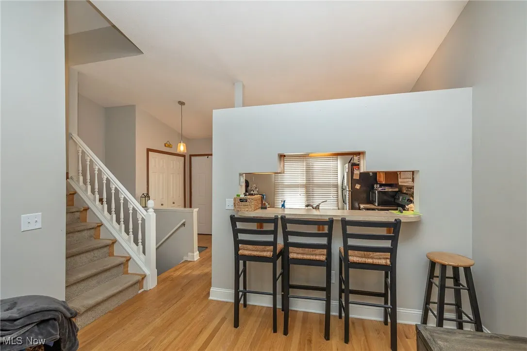 Kitchen featuring a kitchen breakfast bar, light countertops, light wood finished floors, and pendant lighting
