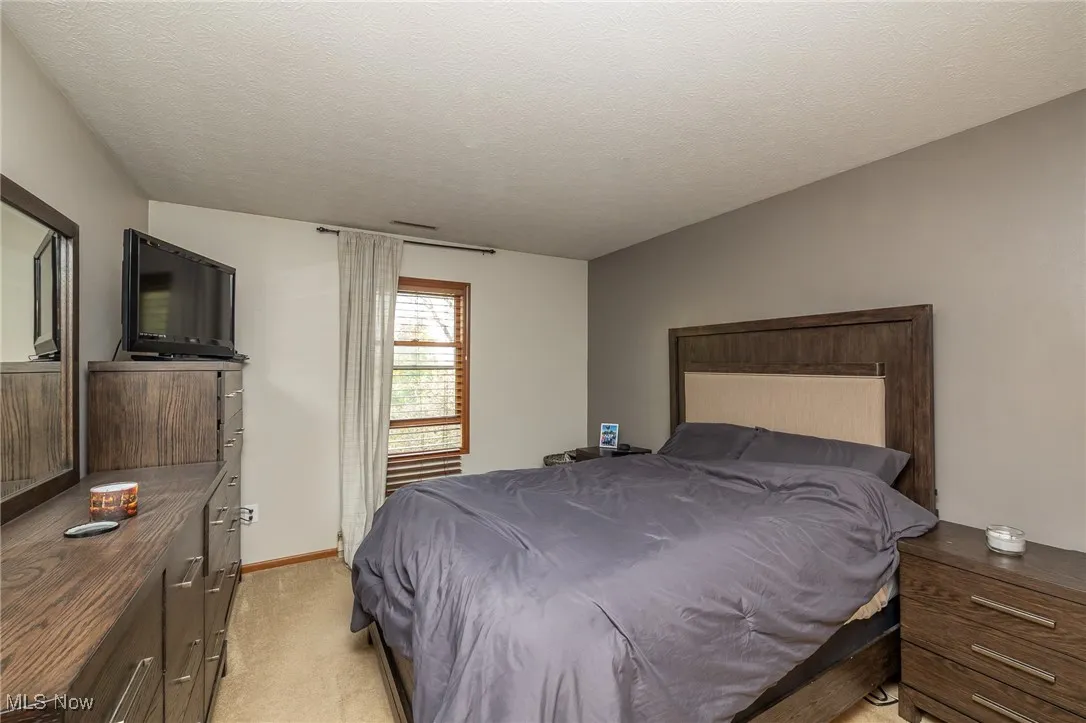 Bedroom featuring a textured ceiling and light colored carpet