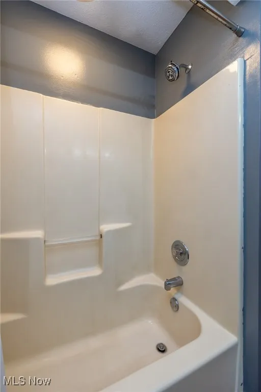 Bathroom featuring  shower combination and a textured ceiling