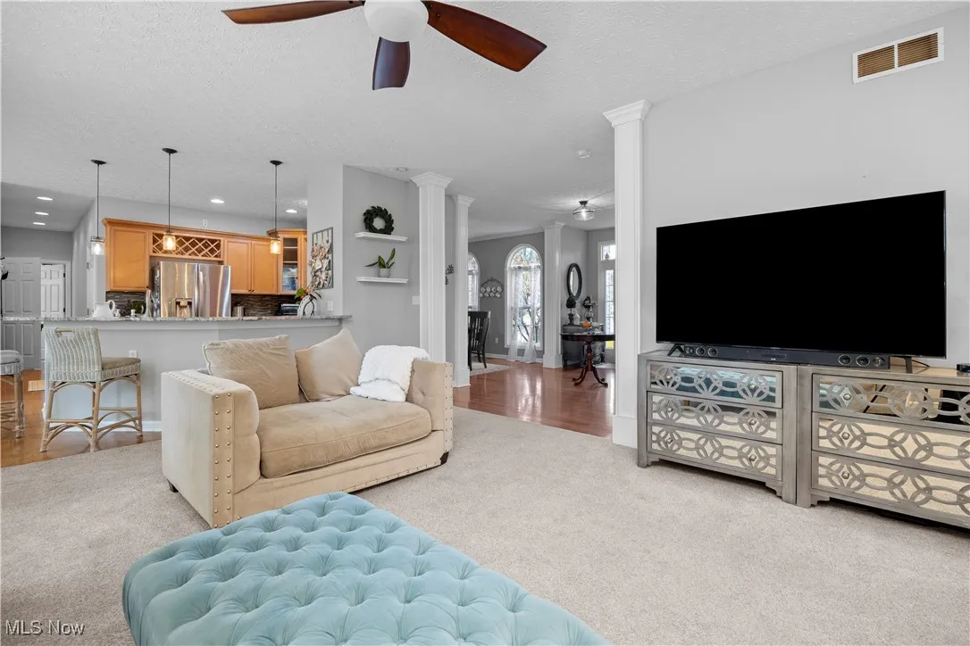 Living area featuring a textured ceiling, ornate columns, a ceiling fan, light carpet, and recessed lighting