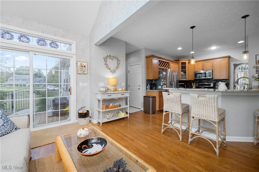 Kitchen with glass insert cabinets, a textured ceiling, backsplash, pendant lighting, and a breakfast bar area