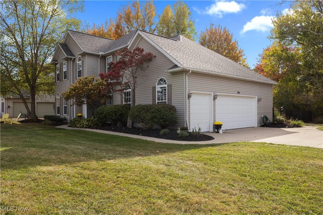 View of side of property with a lawn, a shingled roof, concrete driveway, and an attached garage