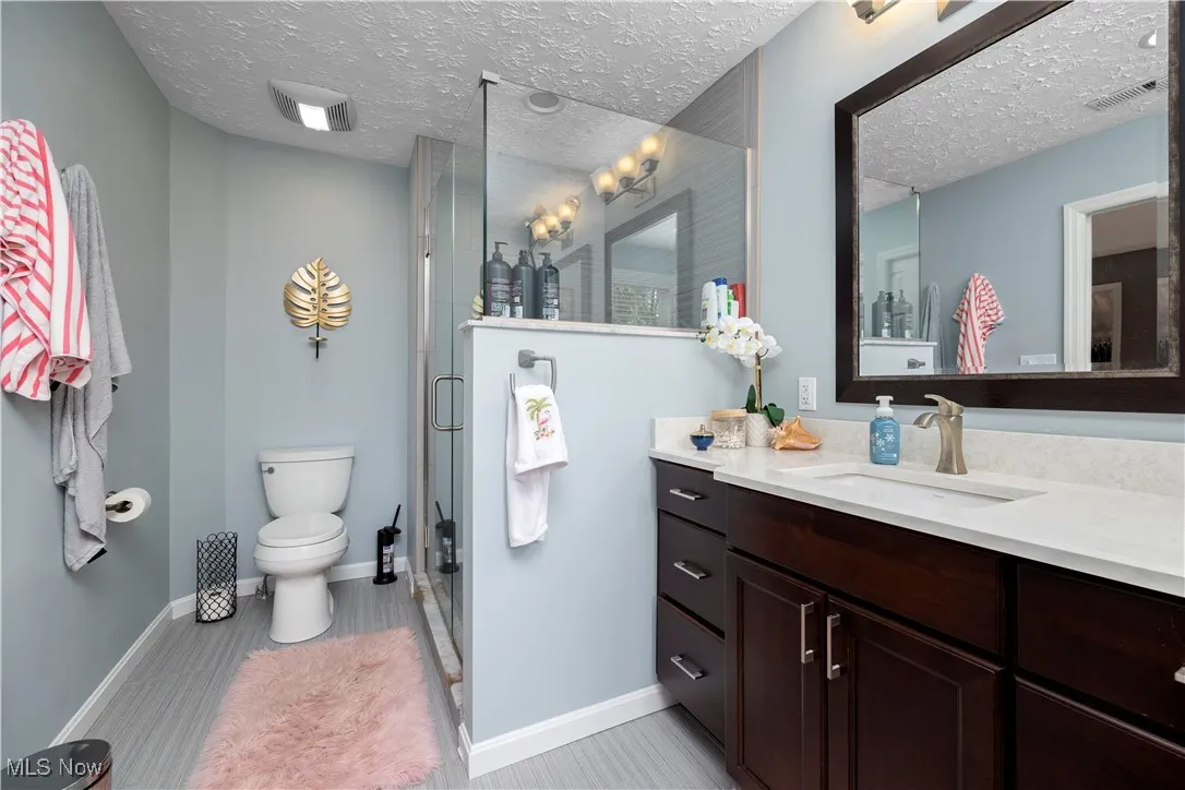 Full bathroom featuring vanity, a stall shower, and a textured ceiling