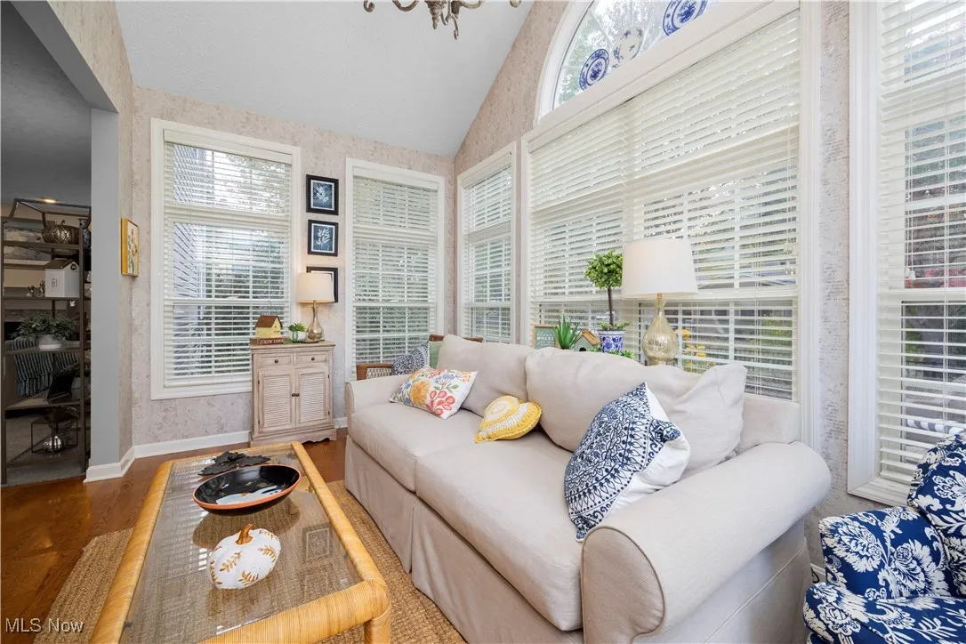 Sunroom / solarium with lofted ceiling, plenty of natural light, and a chandelier