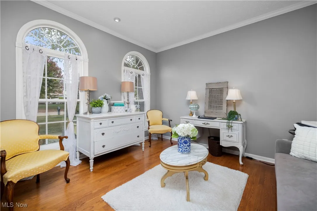 Living area with crown molding and wood finished floors