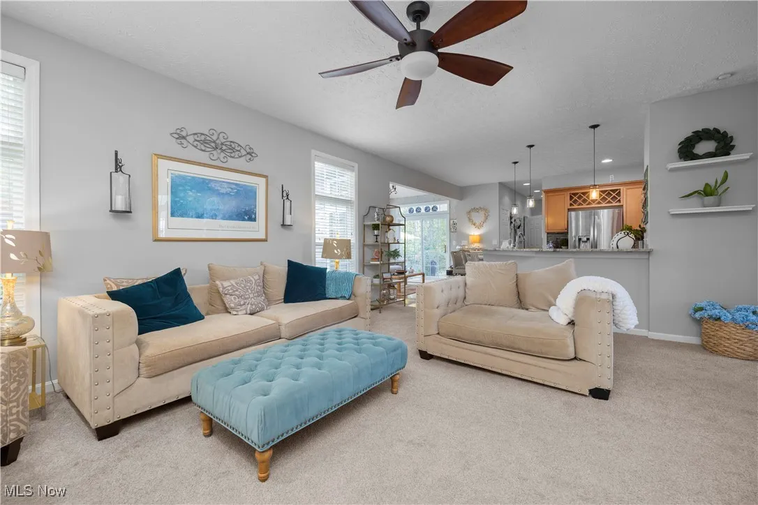 Carpeted living area featuring ceiling fan and a textured ceiling