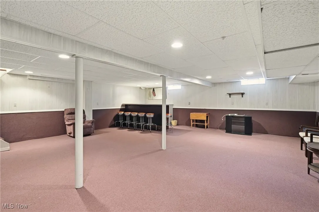 Finished below grade area featuring wood walls, a wainscoted wall, carpet floors, a paneled ceiling, and recessed lighting