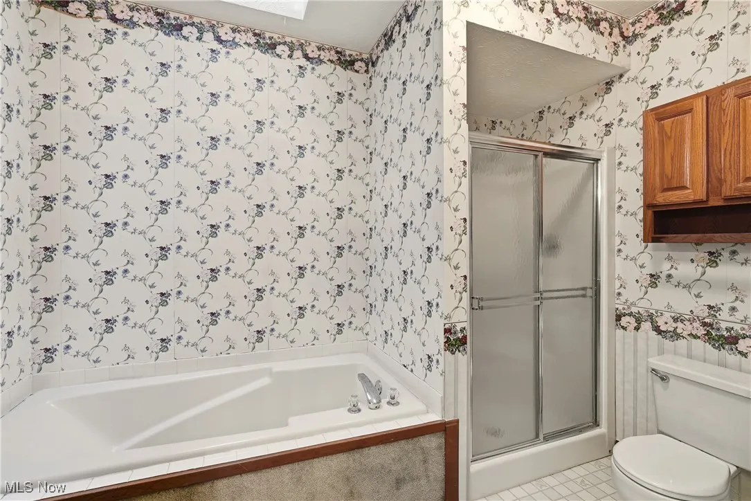 Bathroom with wallpapered walls, a stall shower, a garden tub, and light tile patterned floors