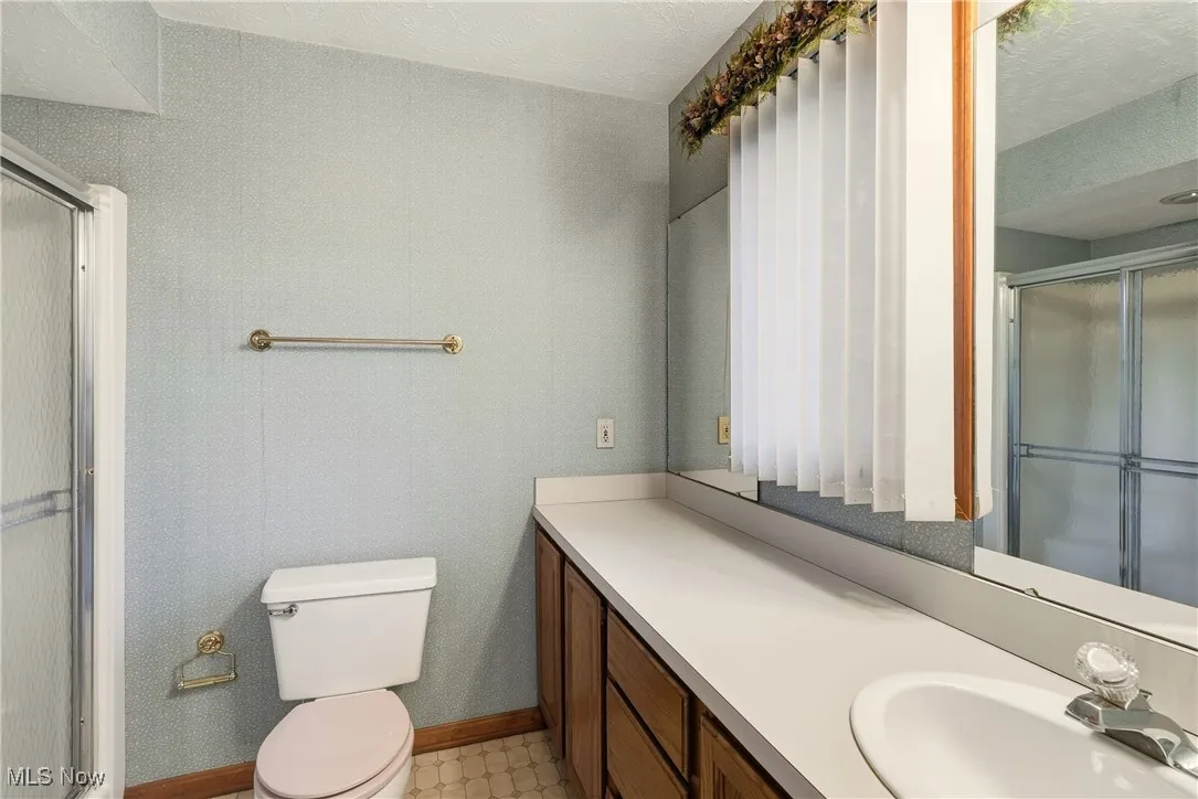 Bathroom featuring vanity, a stall shower, and a textured ceiling