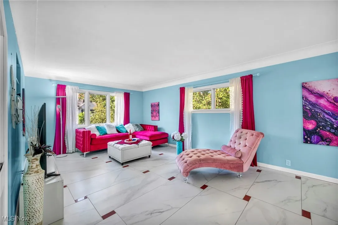 Living room featuring marble look tile flooring and crown molding