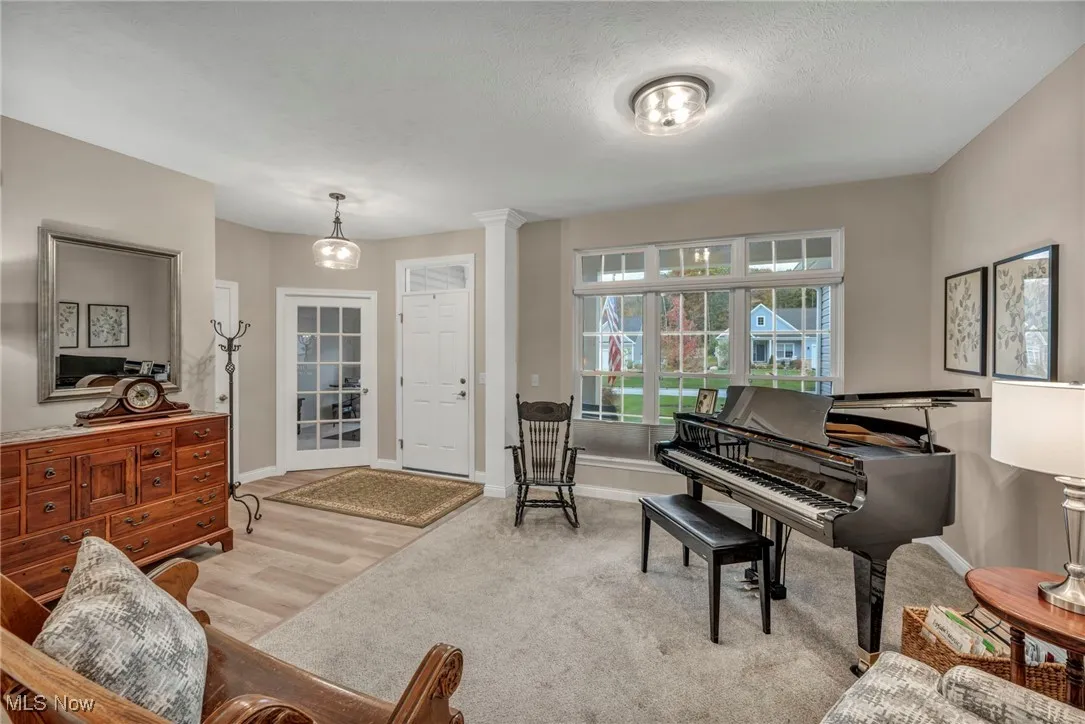 Sitting room with light wood finished floors, a textured ceiling, light colored carpet, and ornate columns